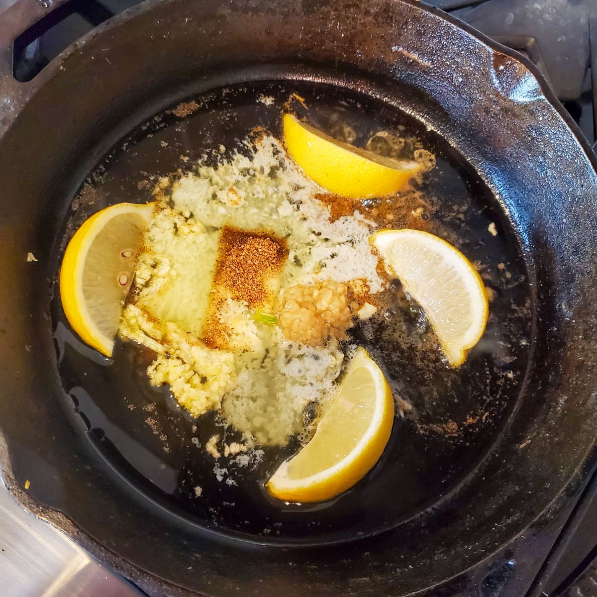 Garlic and lemon cooking in a cast iron pan.