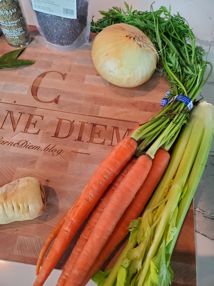 Carrots, celery, on onion on a cutting board.