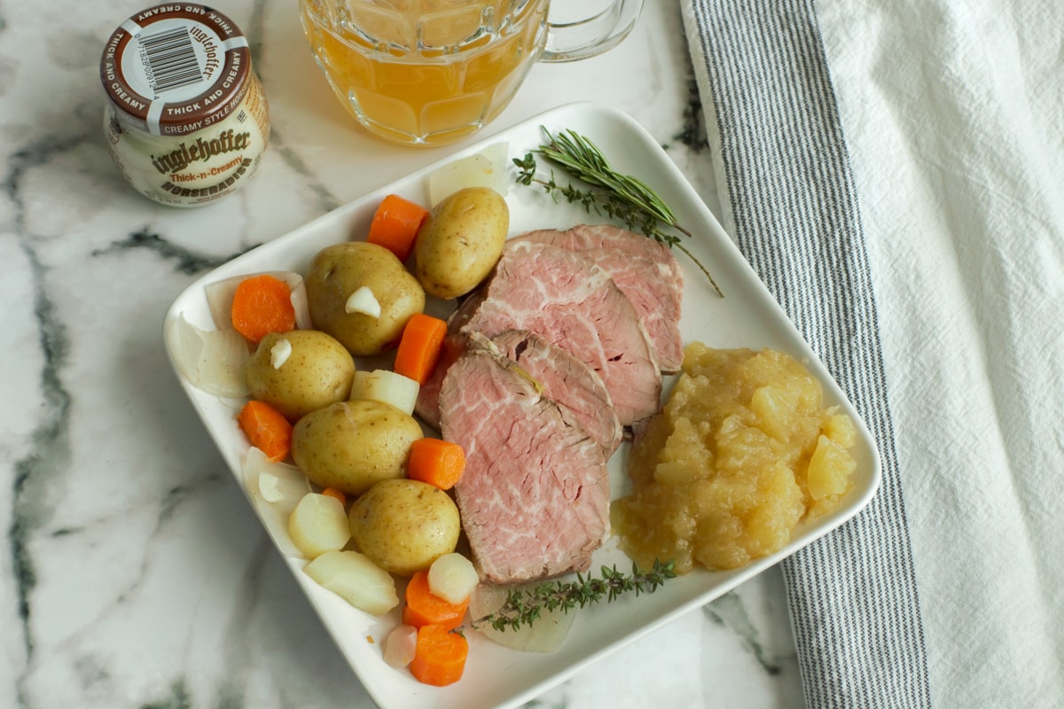 Slices of sous vide tri tip tafelspitz served with potatoes, veggies, applesauce, and a mug of beer.
