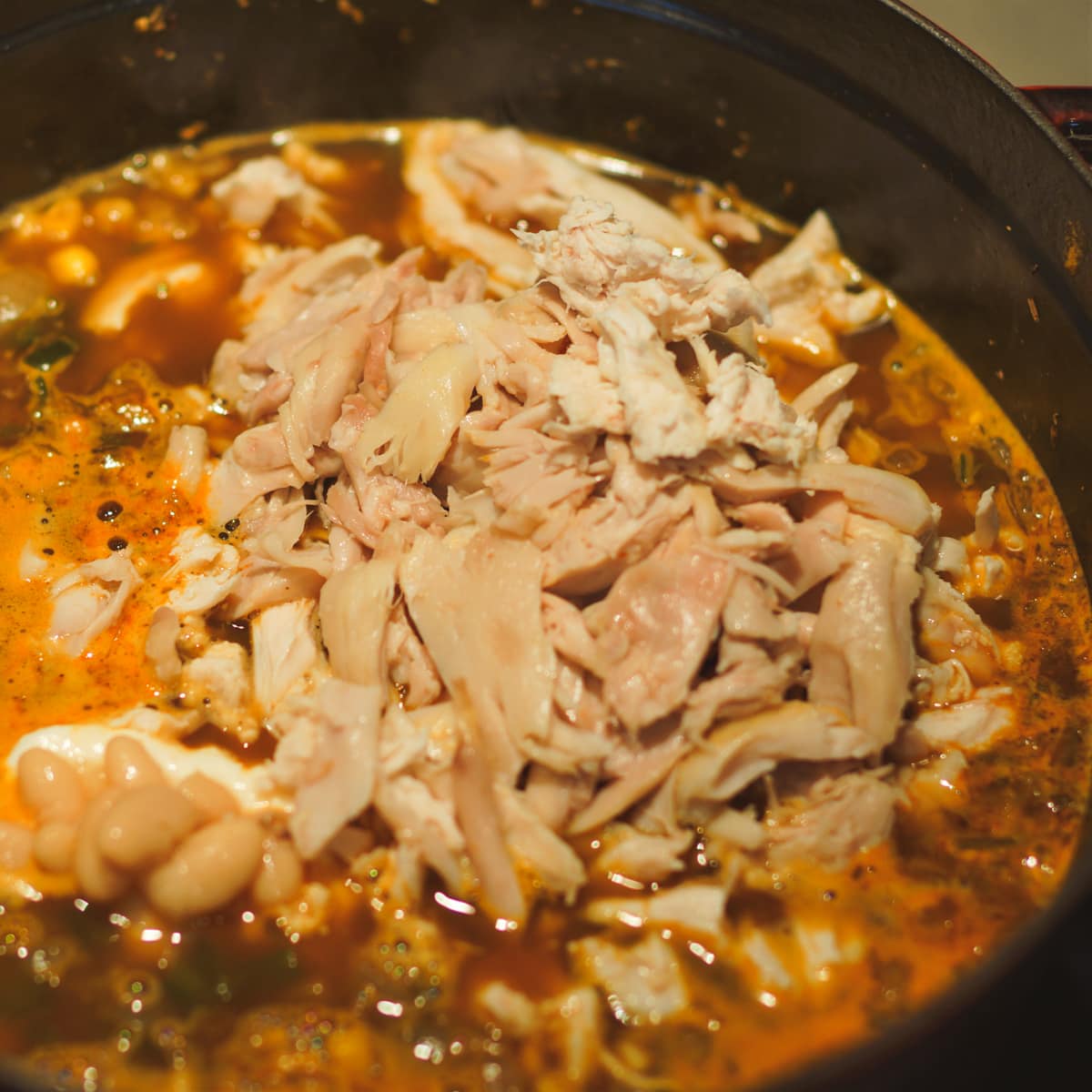 Smoked chicken added to a pot of white chicken chili.