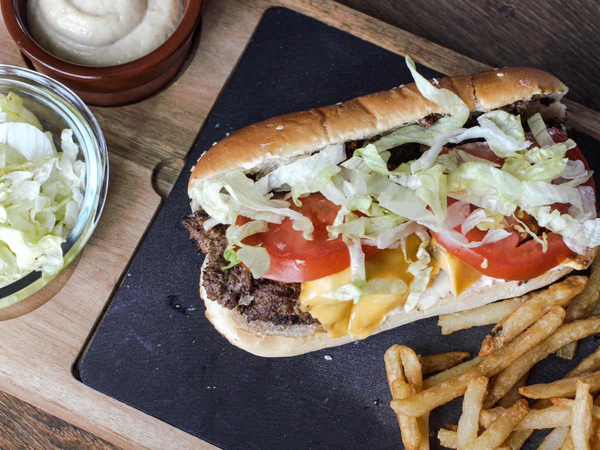 The best chopped cheese sandwich on a plate with fries and garlic aioli.