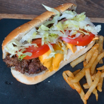 New York Chopped Cheese Sandwich on a slate plate with fries.