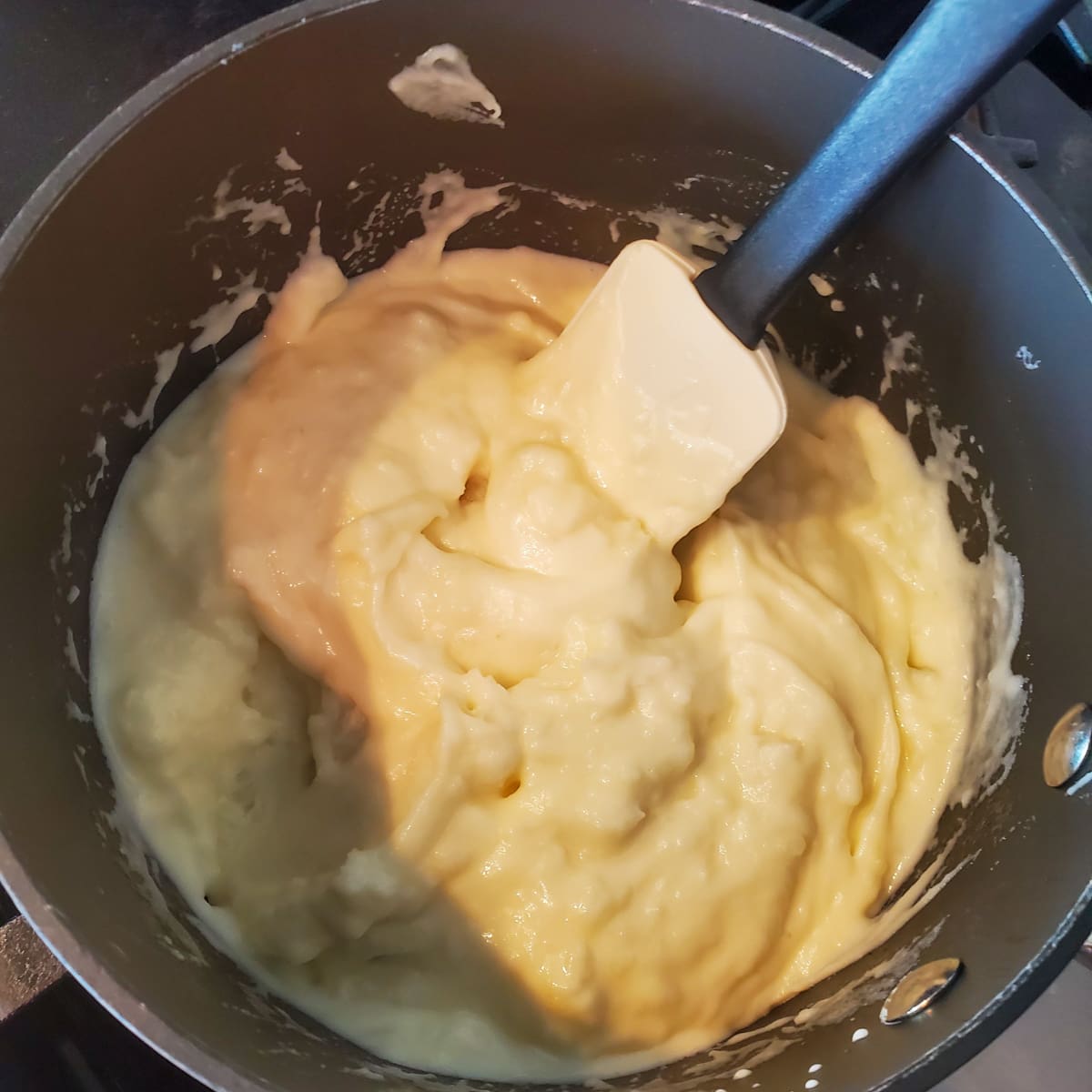 Cream and butter being mixed into mashed potatoes.