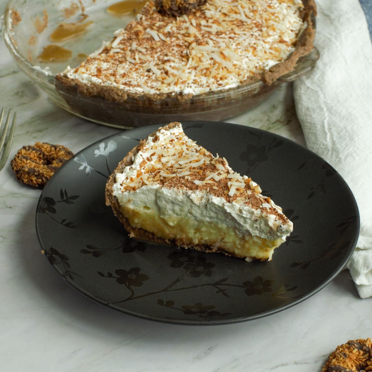 Rish and creamy slice of coconut cream pie with a cookie crust and caramel.