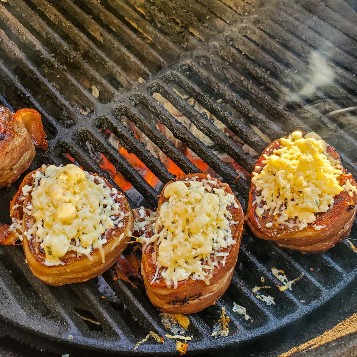 Quattro formaggi crusted steaks on a grill.