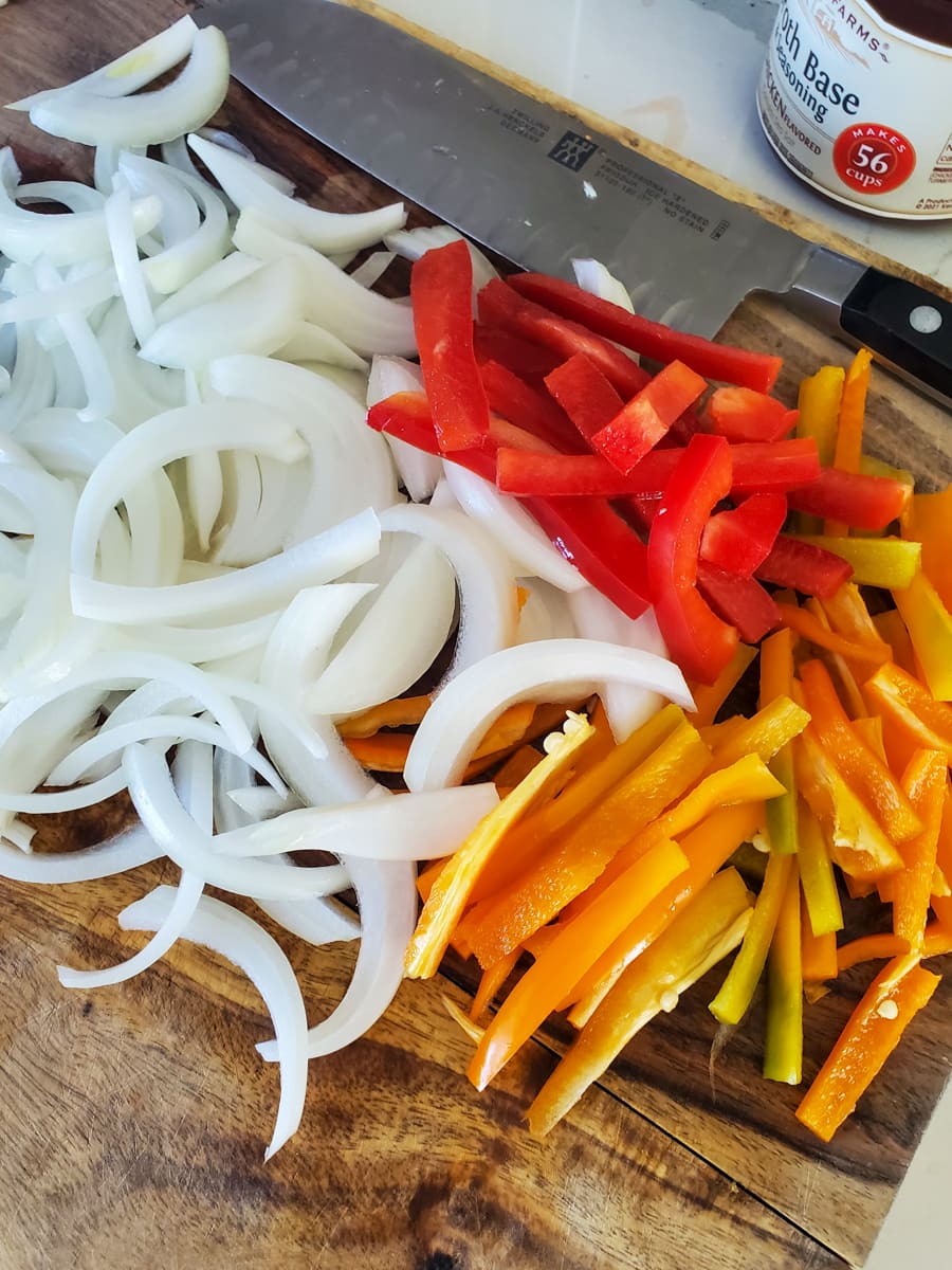 Julienned peppers, onion, and carrots on a cutting board.