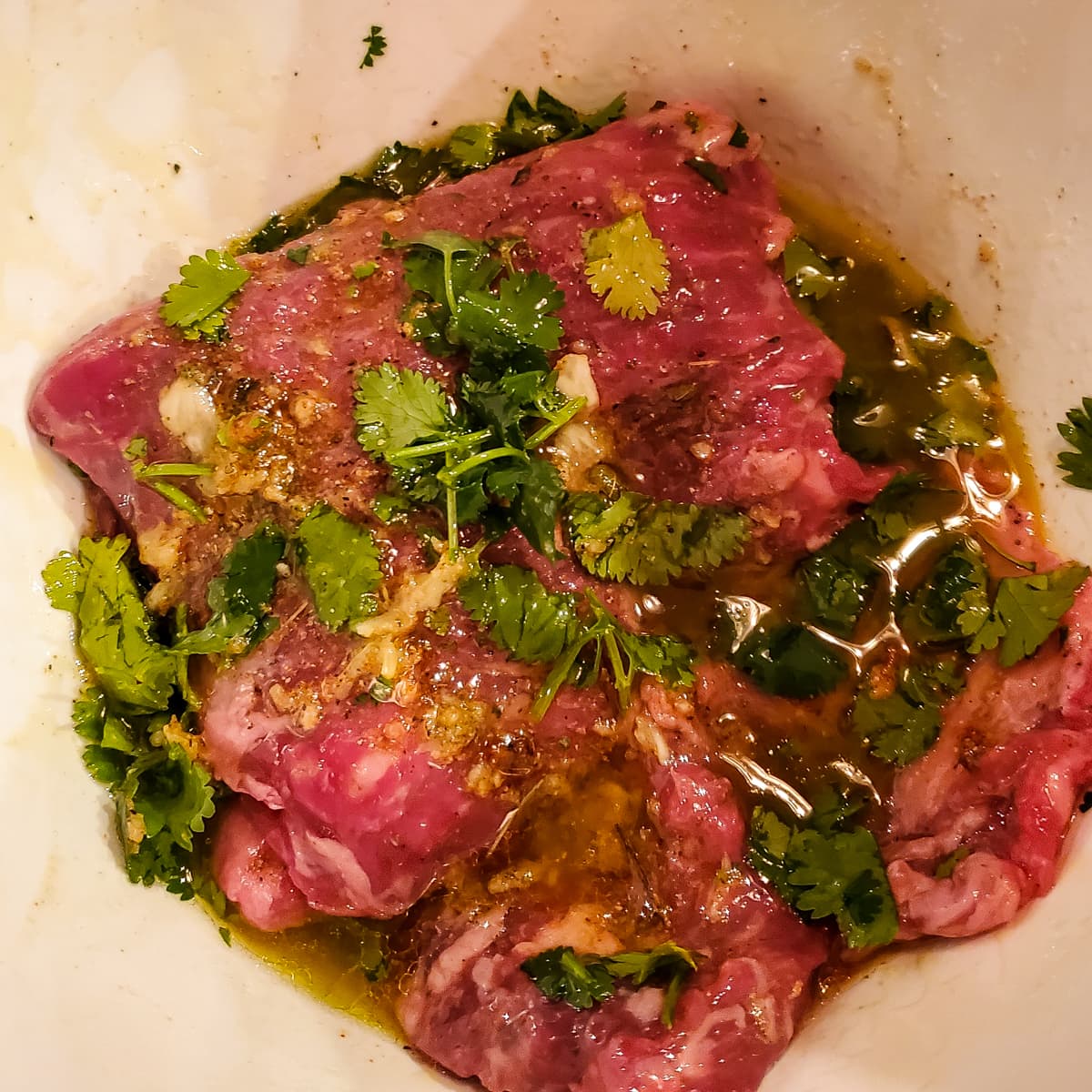 Skirt steak for authentic carne asada in a marinade.