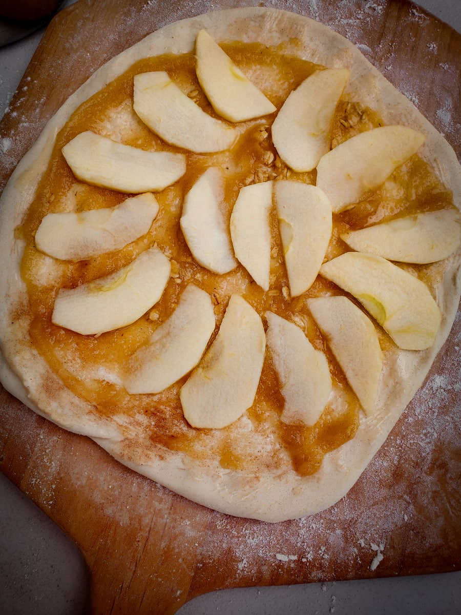Dessert pizza topped with applesauce, cinnamon sugar and apples.