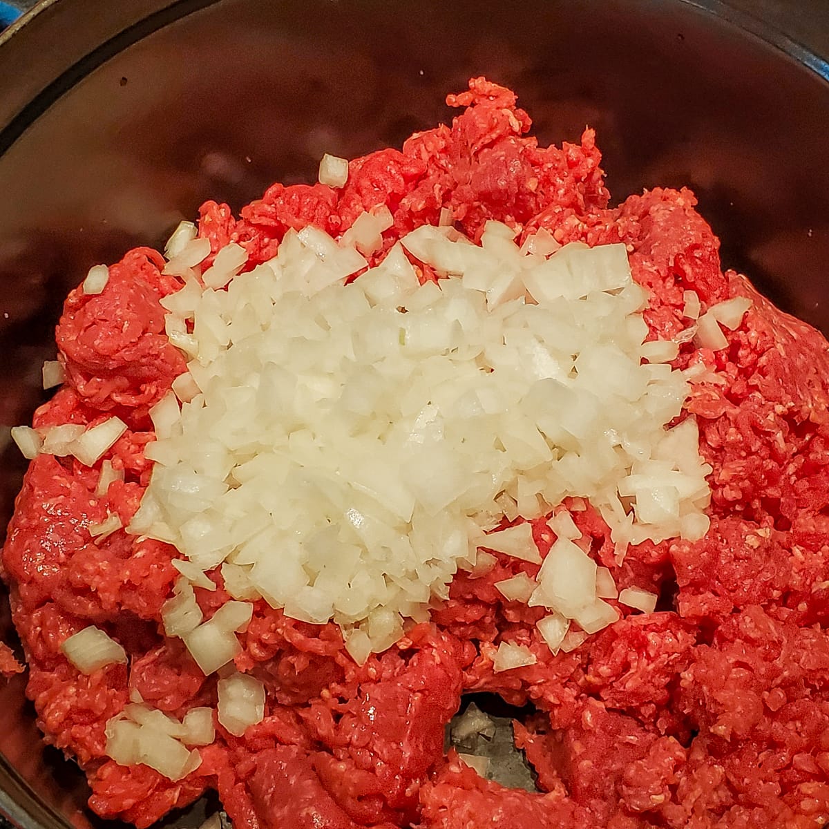 Ground beef and onion cooking in a Dutch oven.