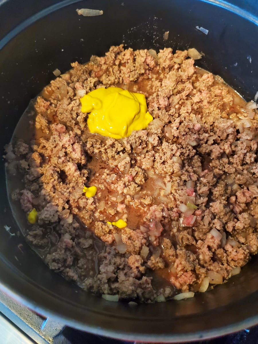 Mustard being added to a Dutch oven of meat for Maid Rite Sandwiches.