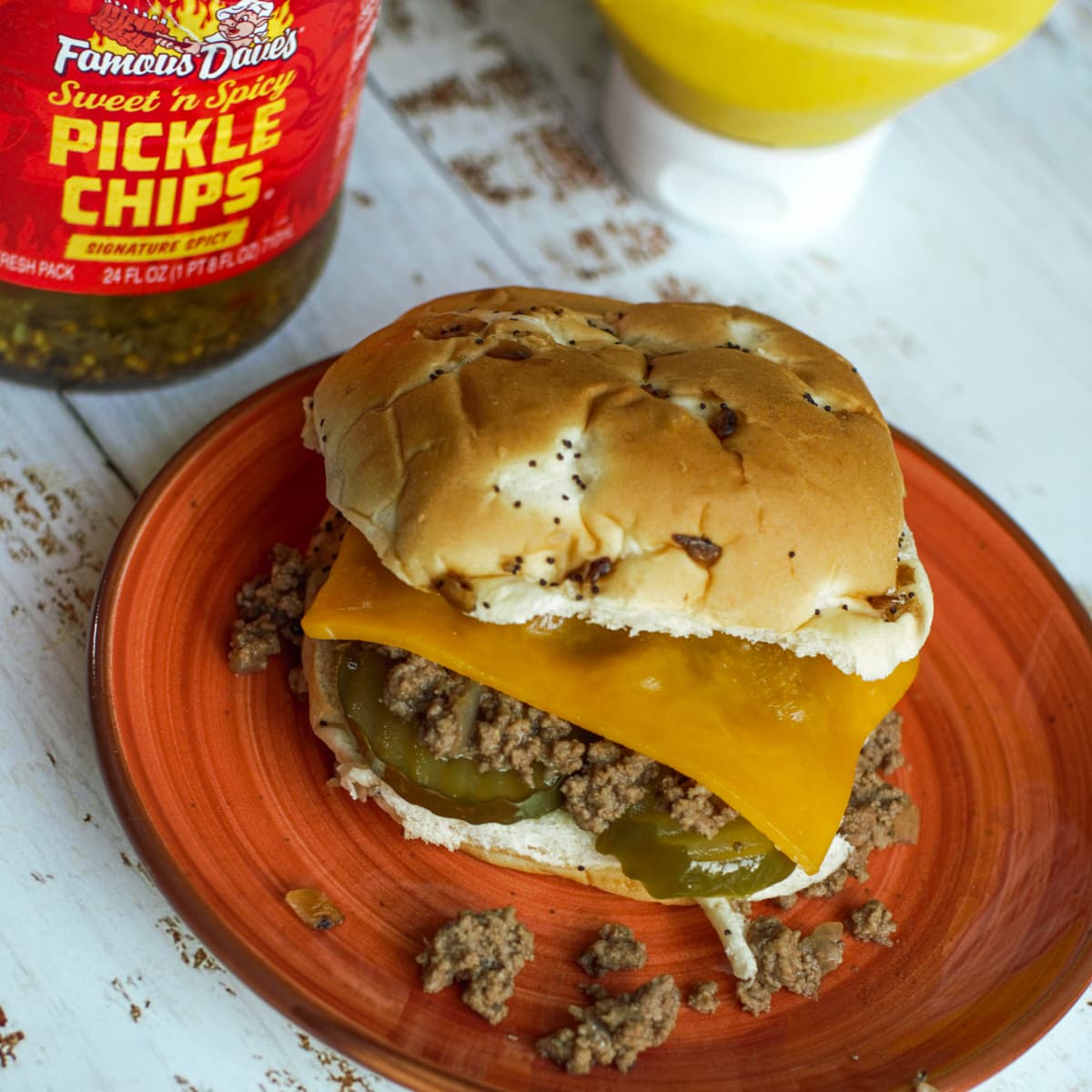 Loose meat sandwich topped with cheese and pickles on an onion bun.