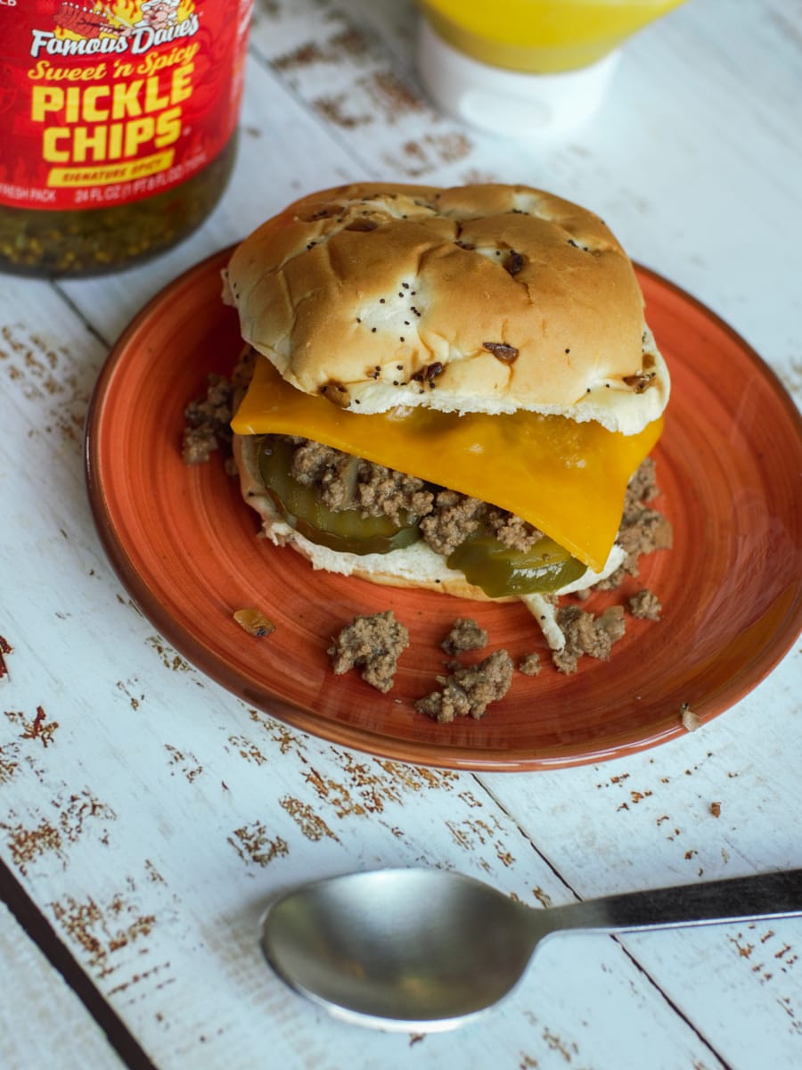 Nu-Way style loose meat sandwich topped with cheese and pickles on an onion bun.