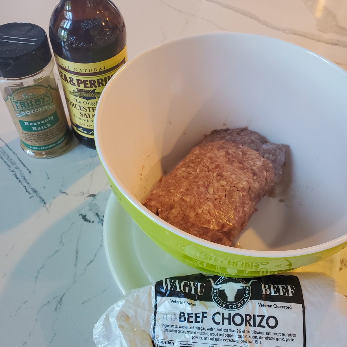 Ground beef, chorizo, Worcestershire sauce, and Hatch seasoning on a counter.