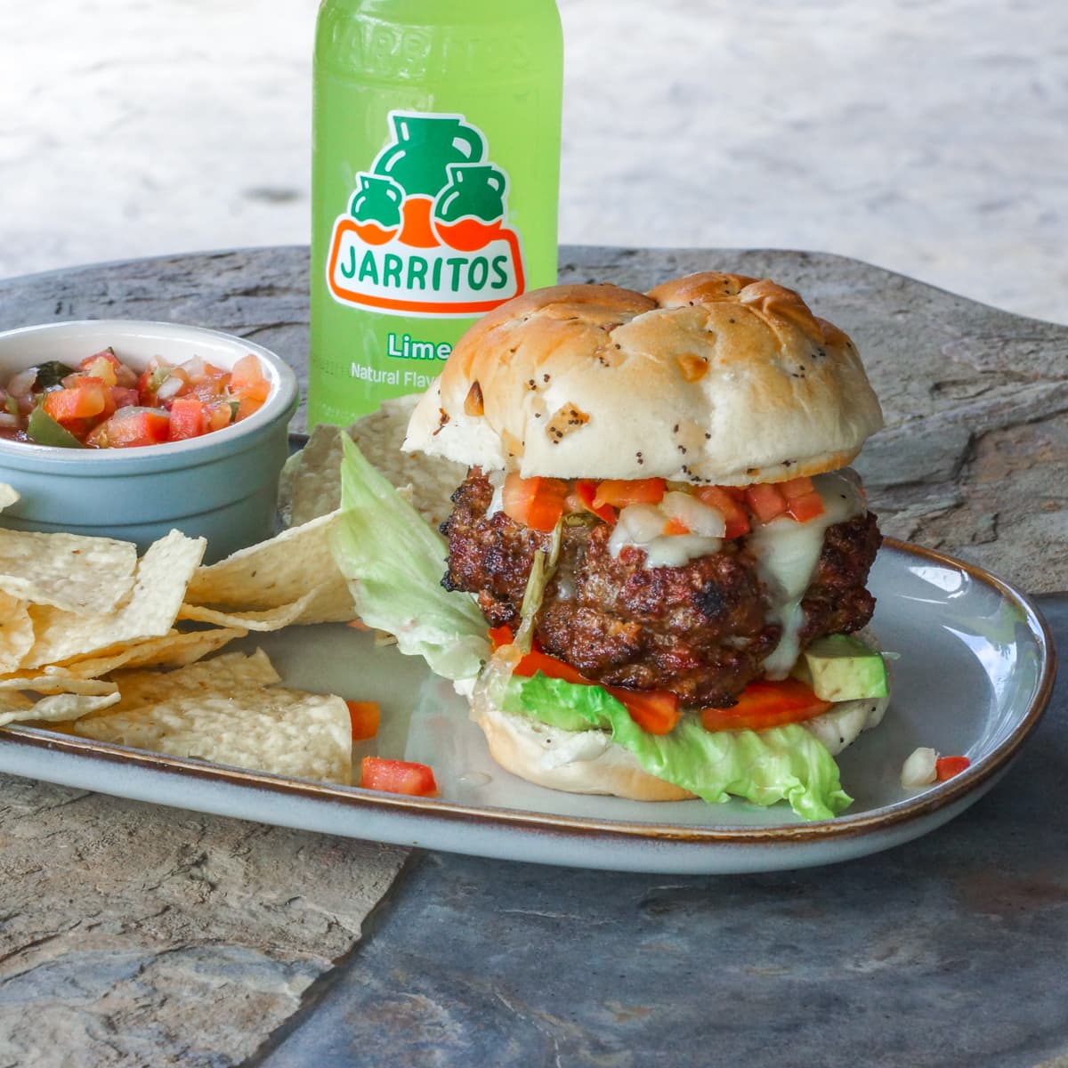Oaxaca cheese stuffed Mexican Chorizo Burger on a plate with chips and Pico de Gallo.