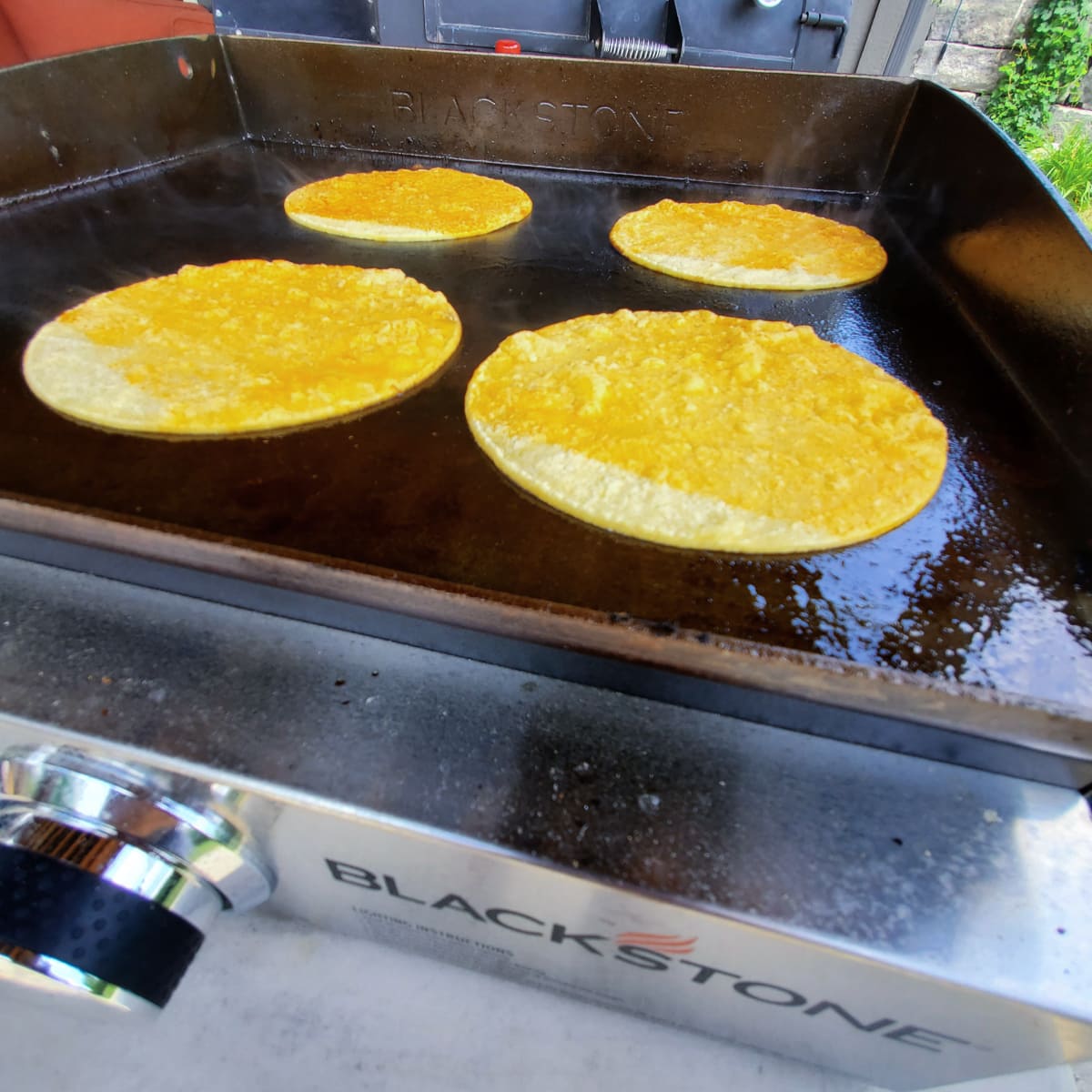 4 corn tortillas on a Blackstone griddle.