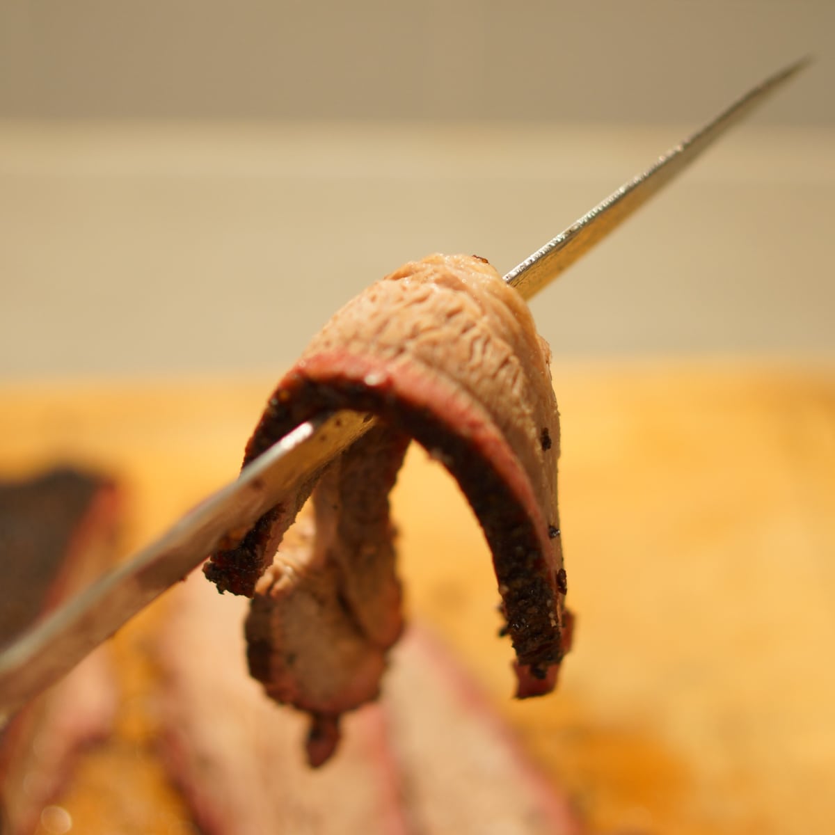 Slice of brisket bending over a knife.