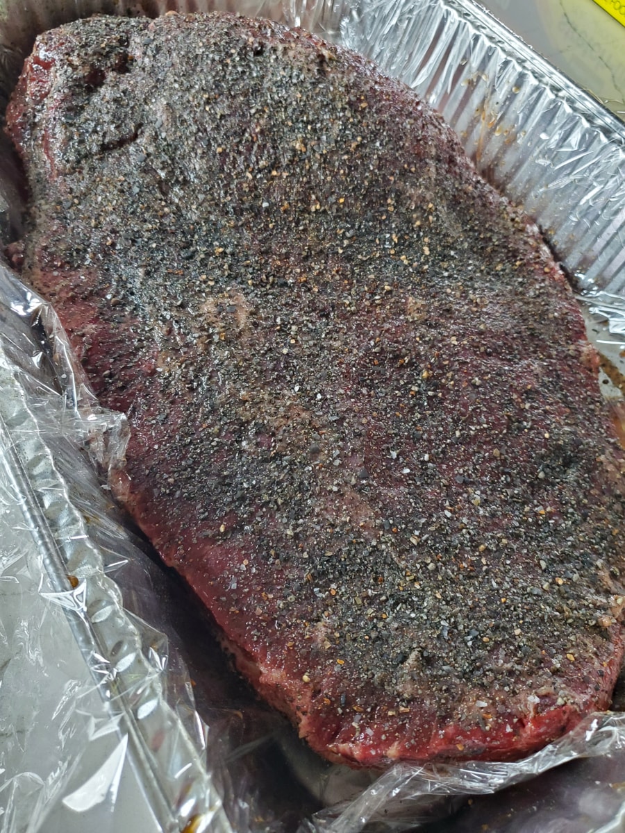 Seasoned brisket in a foil pan.