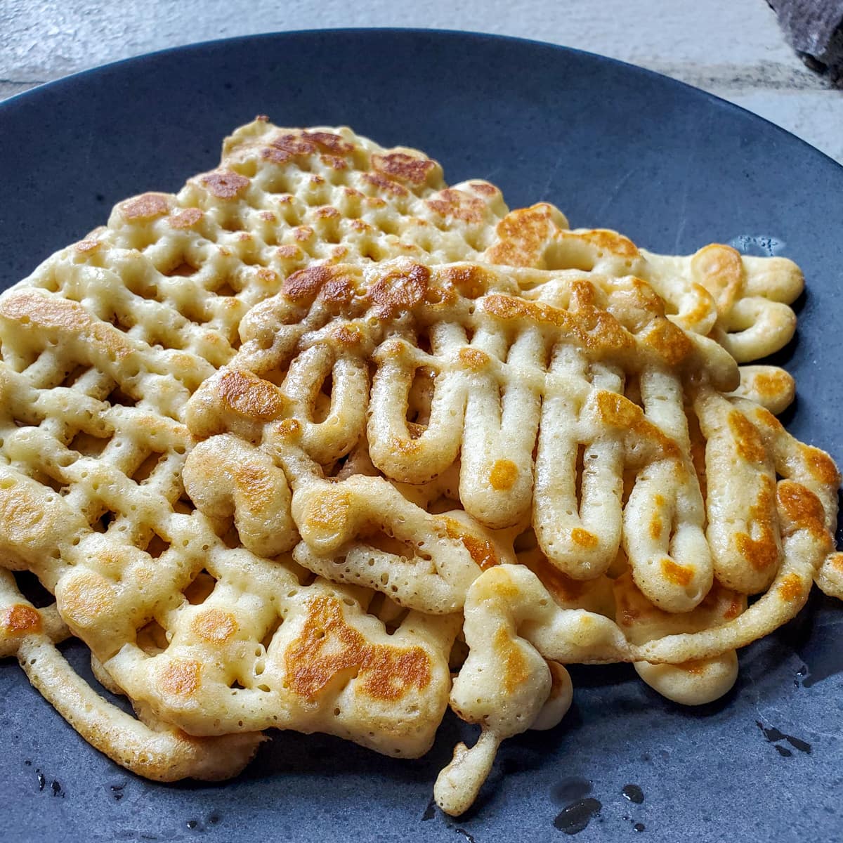 Homemade funnel cakes on a black plate.