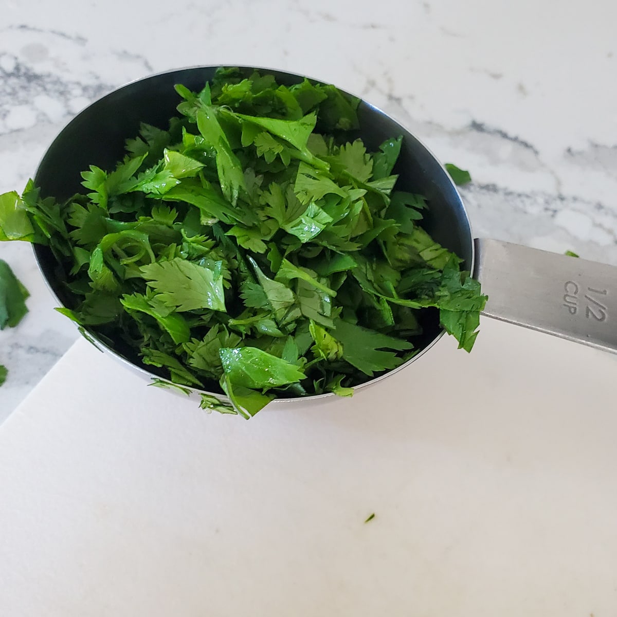 Measuring cup with chopped parsley.