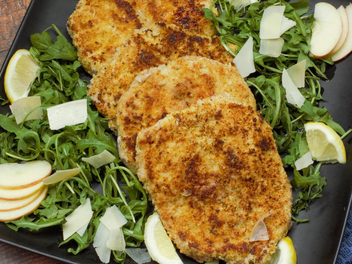 Italian breaded pork Milanese on a plate with arugula. 