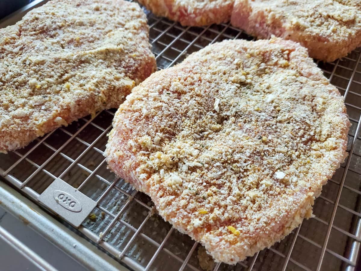 Breaded Italian pork chops on a wire rack.