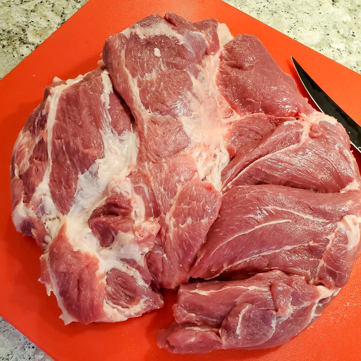 Boneless pork butt, filleted open on a cutting board.