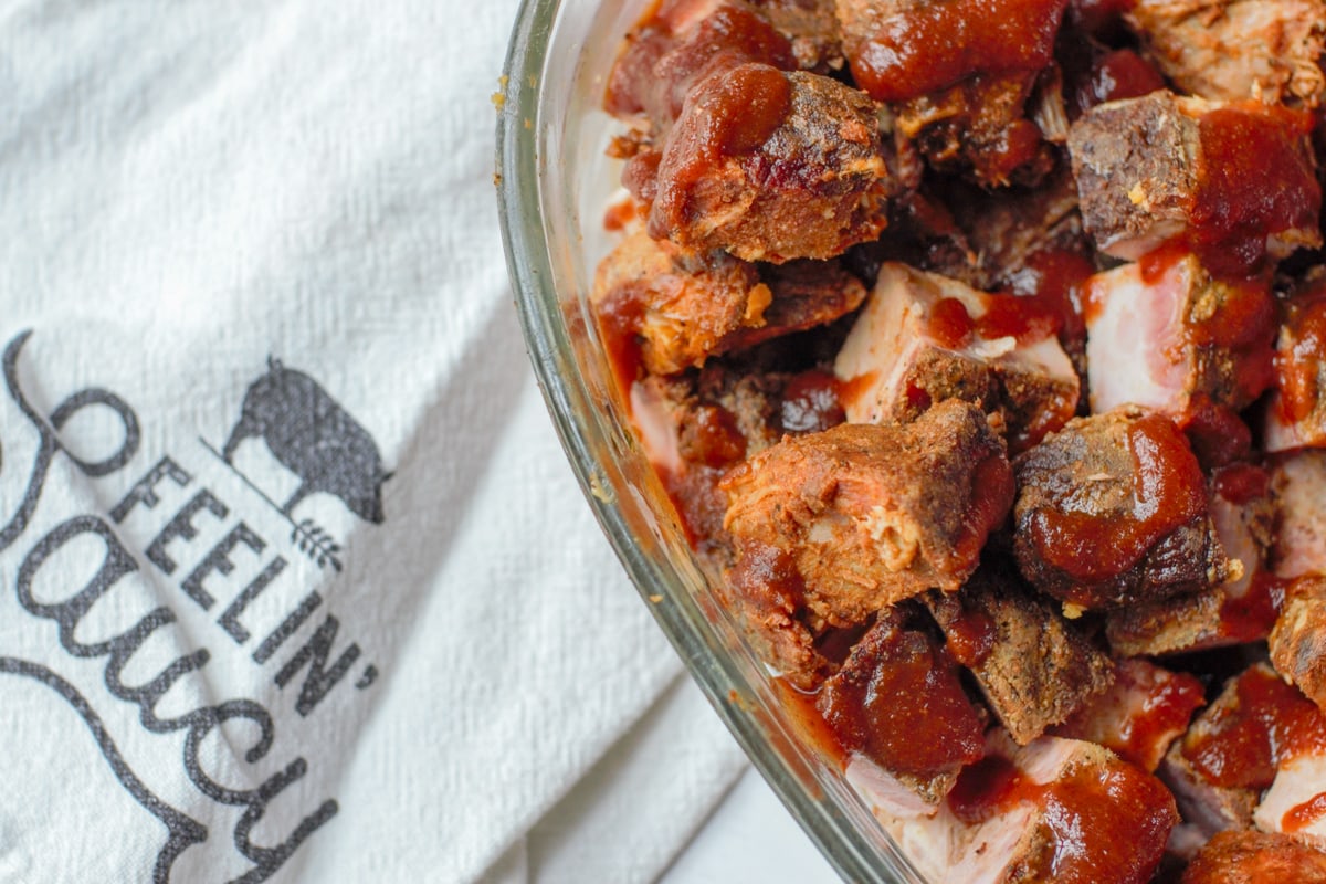 Sauced and smoked pork burnt ends in a glass dish.