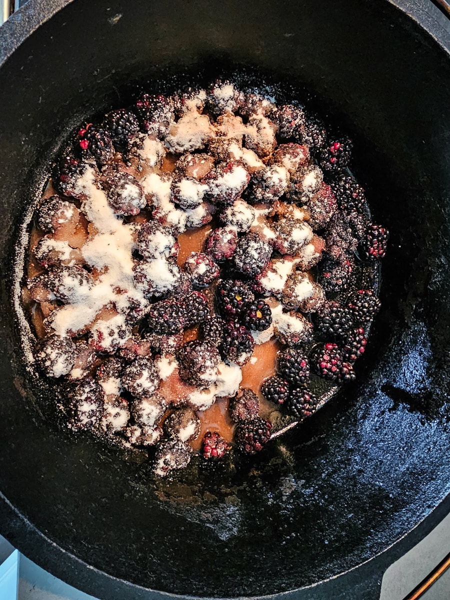 Blackberries simmering with sugar in a Dutch oven.