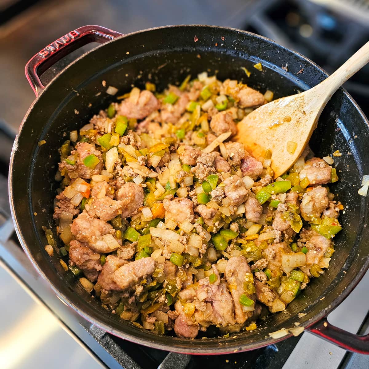 Pork chili verde cooking in a Dutch oven on a stovetop.