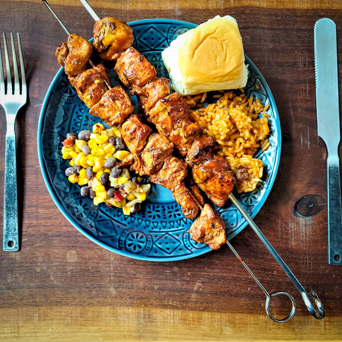 Plate of Peruvian Chicken anticuchos skewers with rice and veggies.