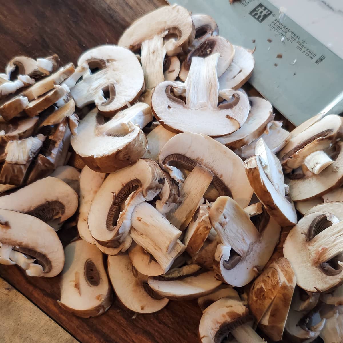 Sliced Baby Bella mushrooms on a cutting board.