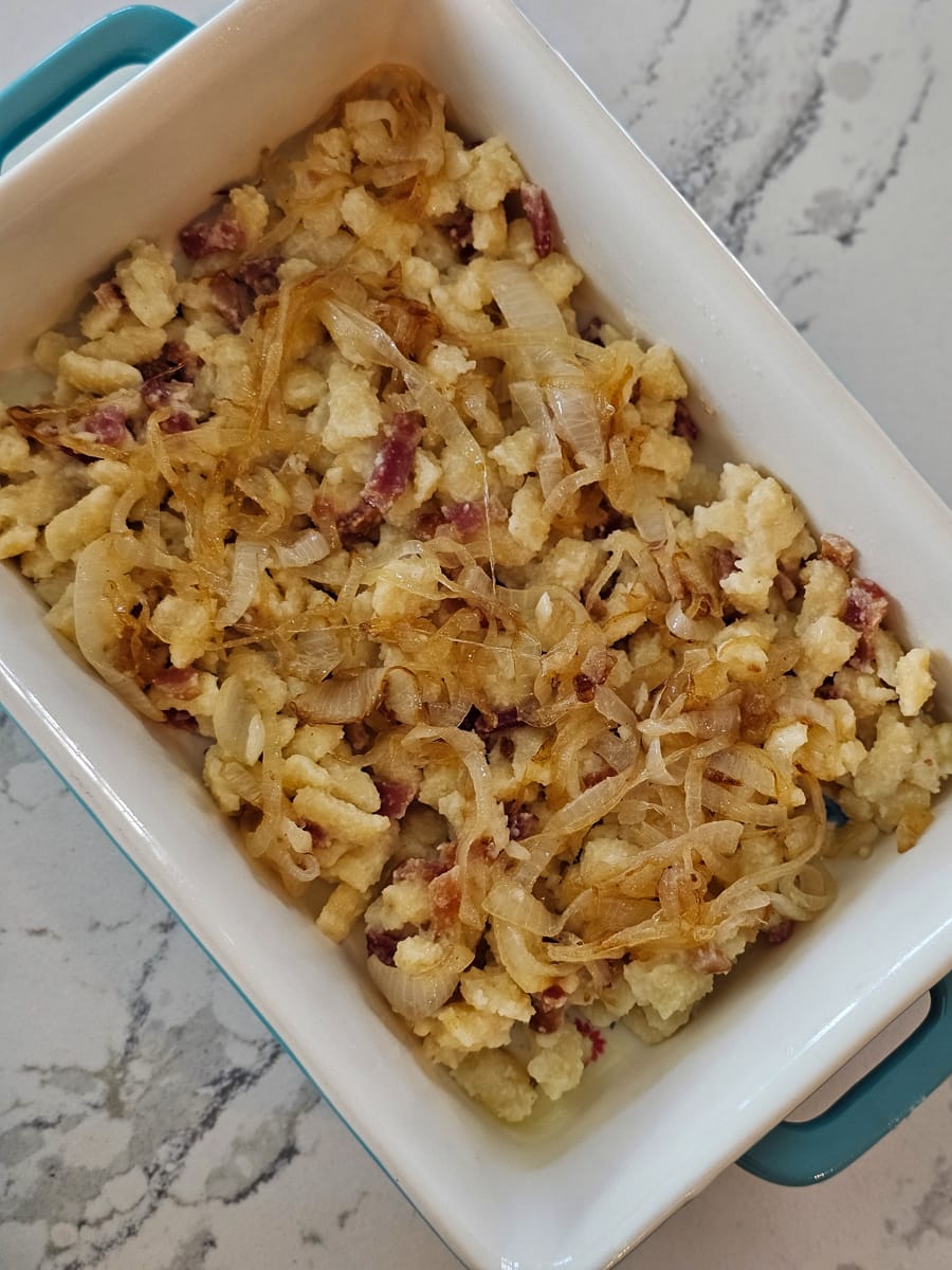 German spaetle layered in a casserole dish with bacon and onion.