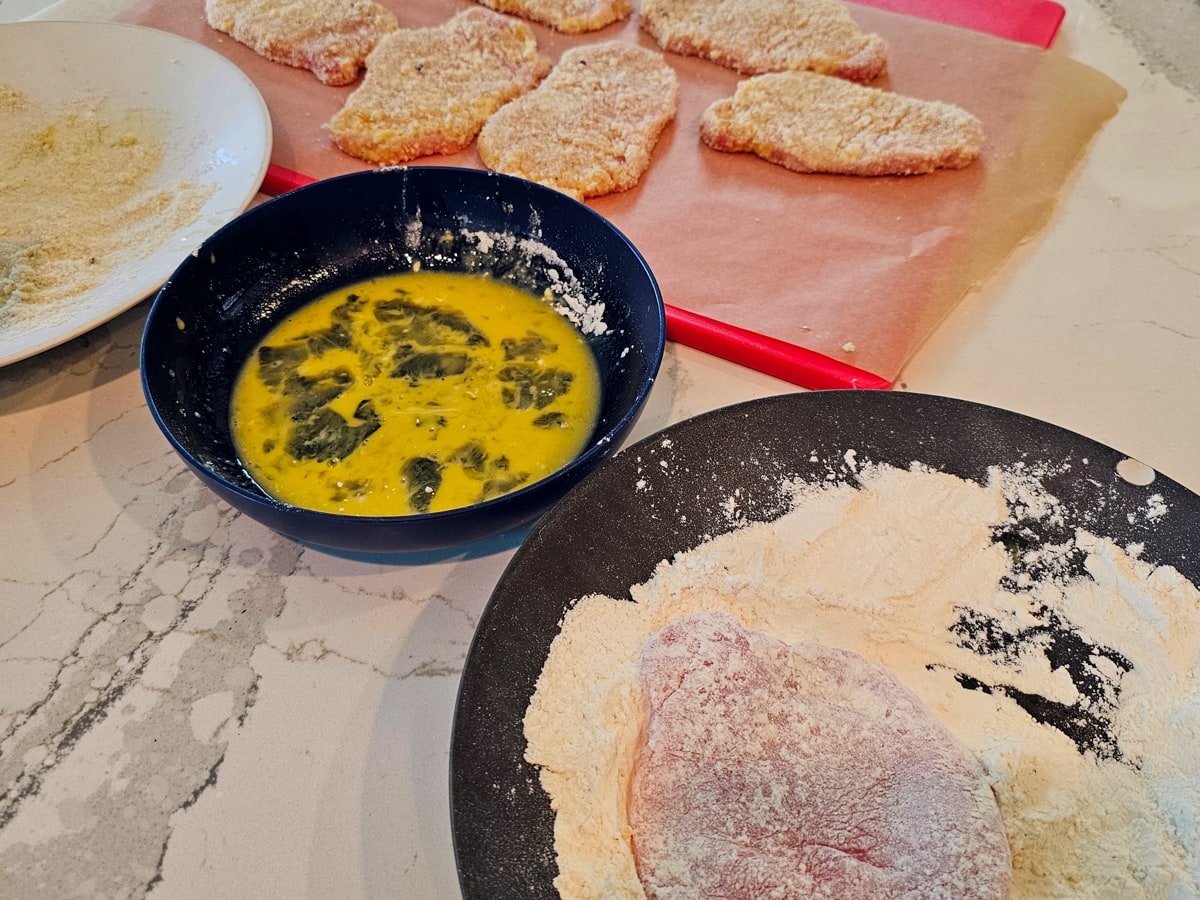 Plates with flour, eggs, and breadcrumbs for breading schnitzel.