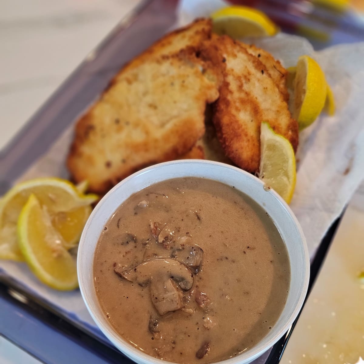 Bowl of German mushroom gravy with a platter of pork schnitzel.