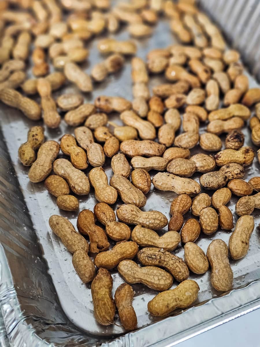 Salted peanuts on a foil pan on a smoker.