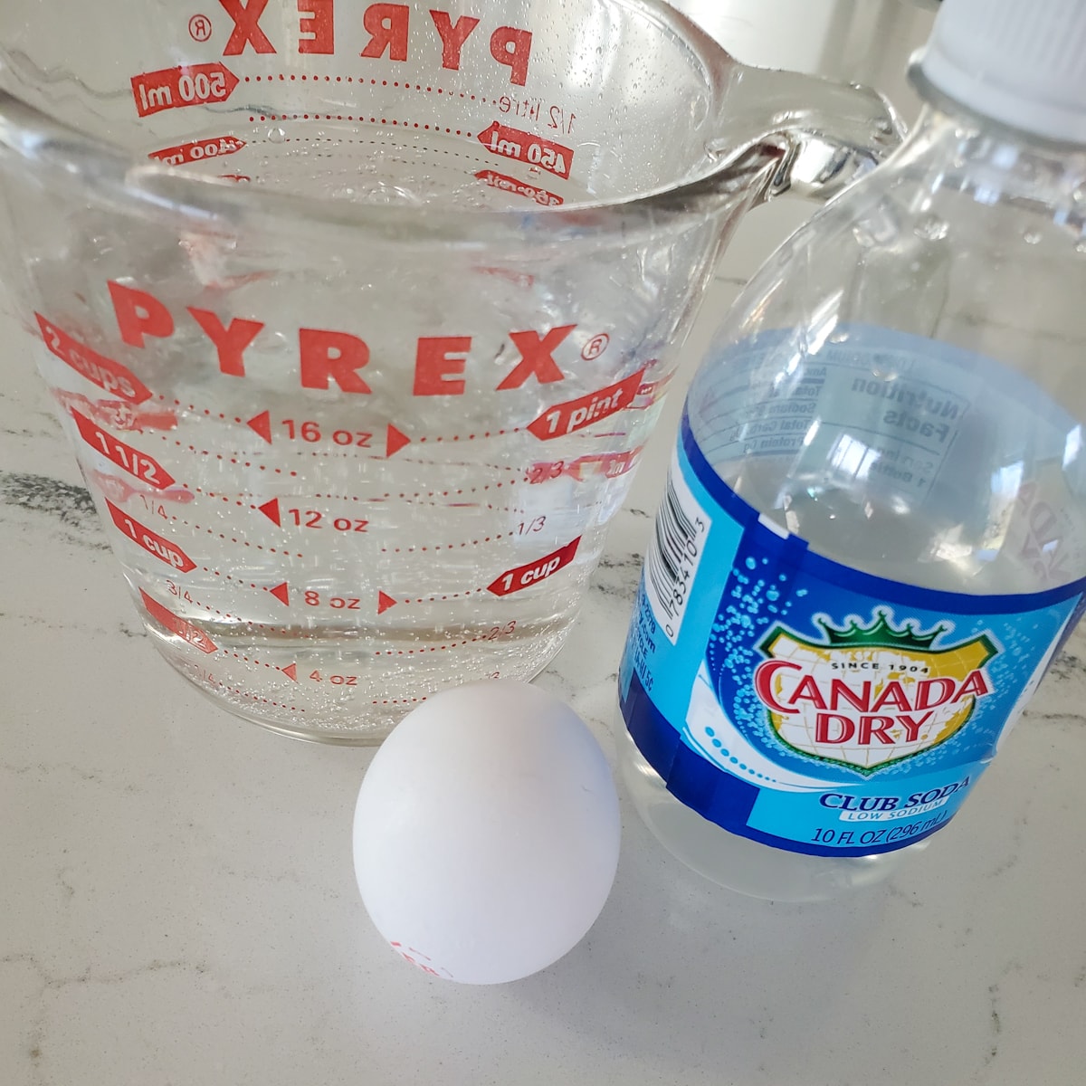 Club soda and an egg on a countertop.