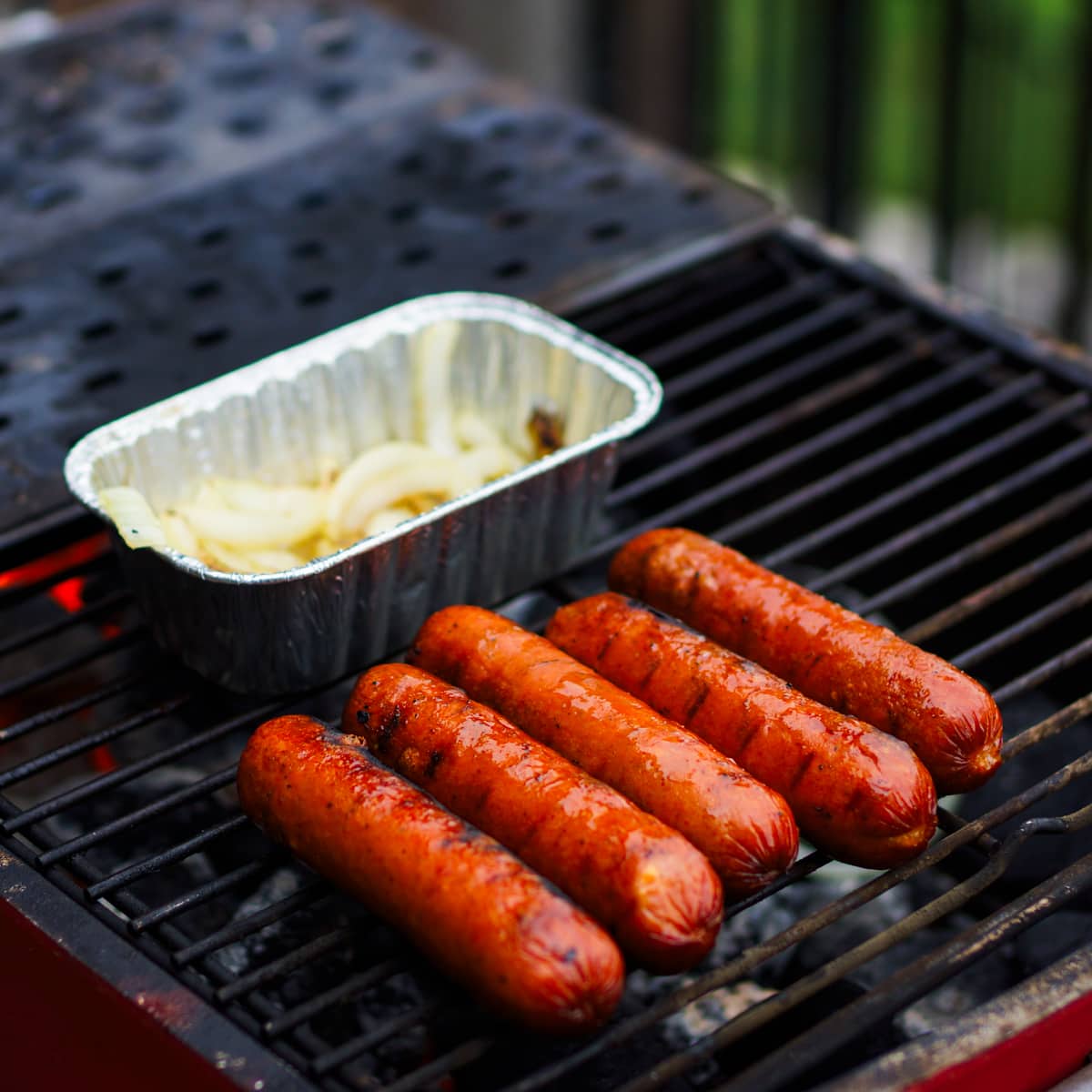 Beef sausages and onions cooking on a PK grill.