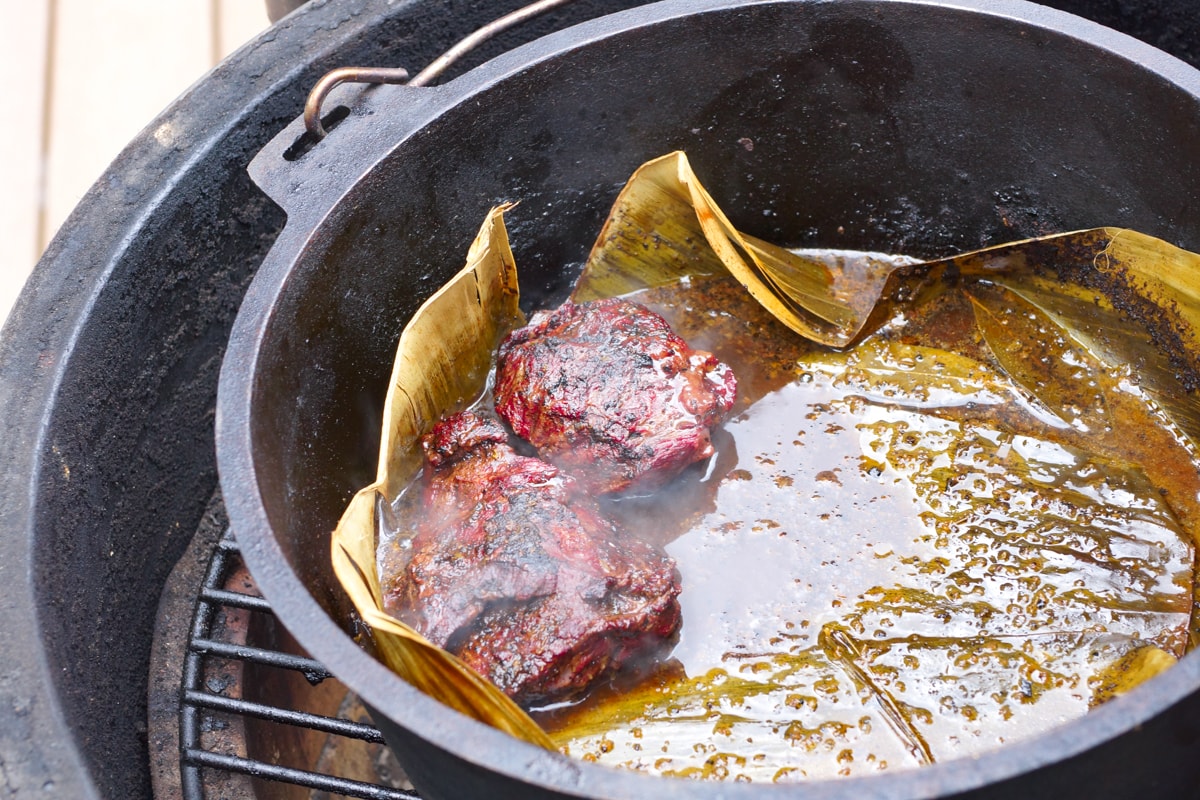 Beef cheek in a Dutch oven on a grill.