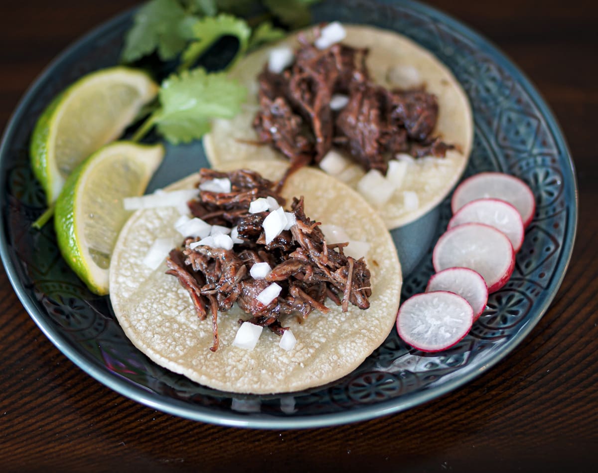 Smoked barbacoa tacos on a decorative plate.