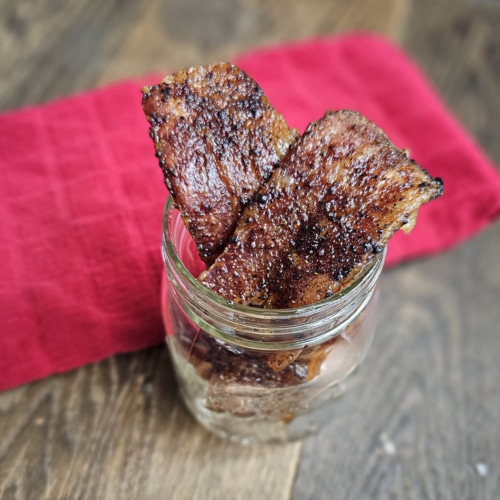 Bloody Mary seasoned bacon slices in a glass jar.