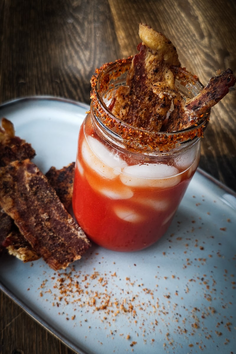 Bloody Mary with seasoned bacon in a Mason jar.