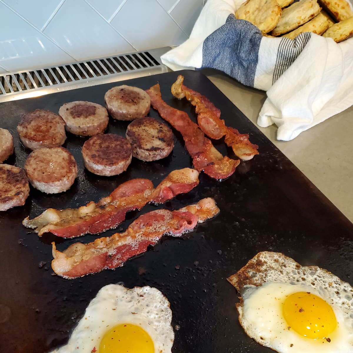 Sausage, bacon, and eggs cooking on a flat top.