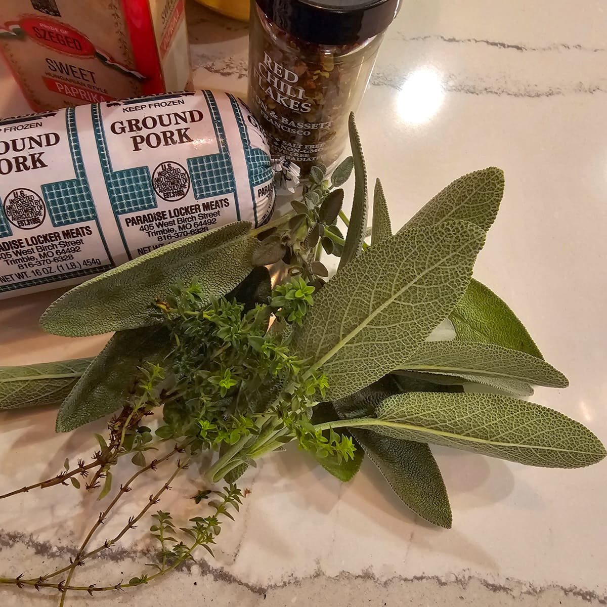 Fresh sage and thyme on a countertop.