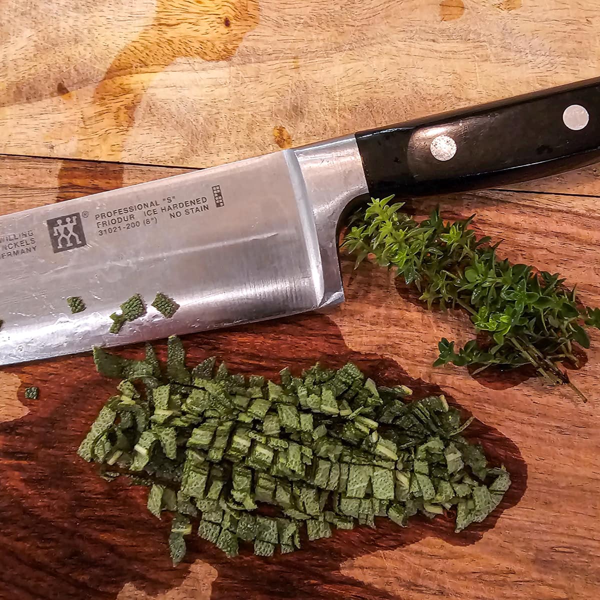 Chopped sage and thyme leaves on a cutting board.