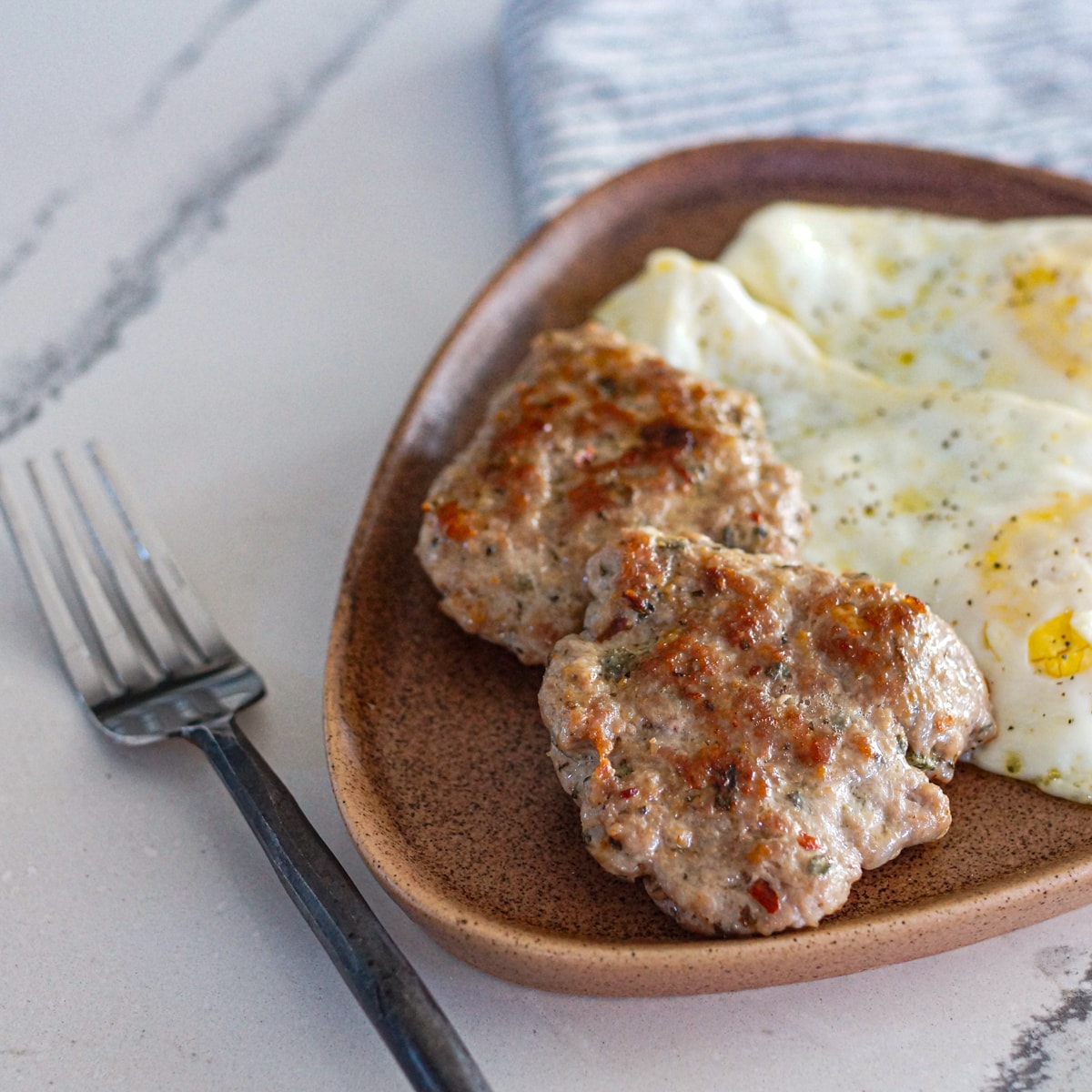 Two sausage patties and eggs on a plate.