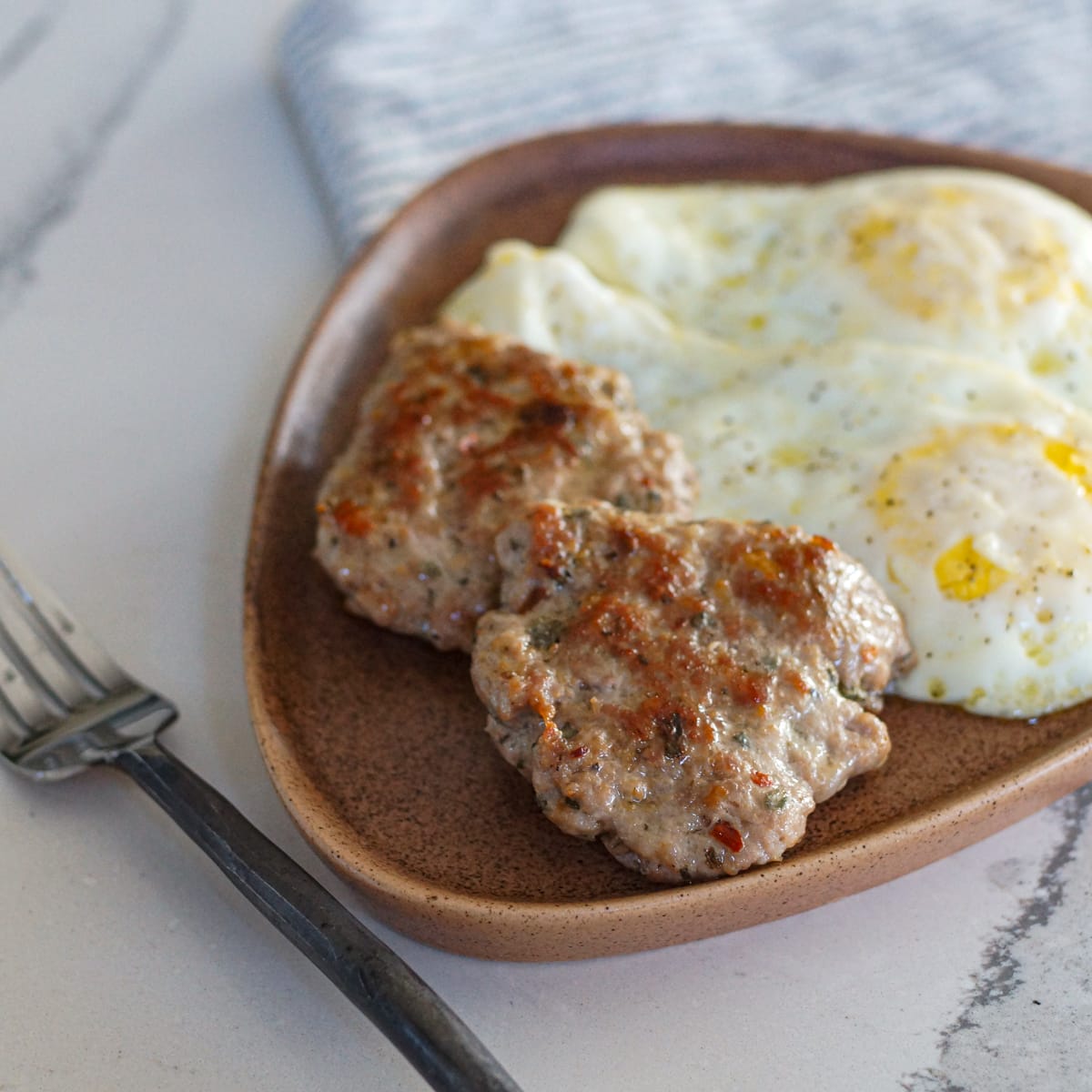 Breakfast plate with homemade sausage and fried eggs.