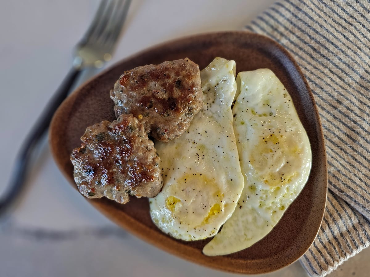 Fresh breakfast sausage patties with eggs.