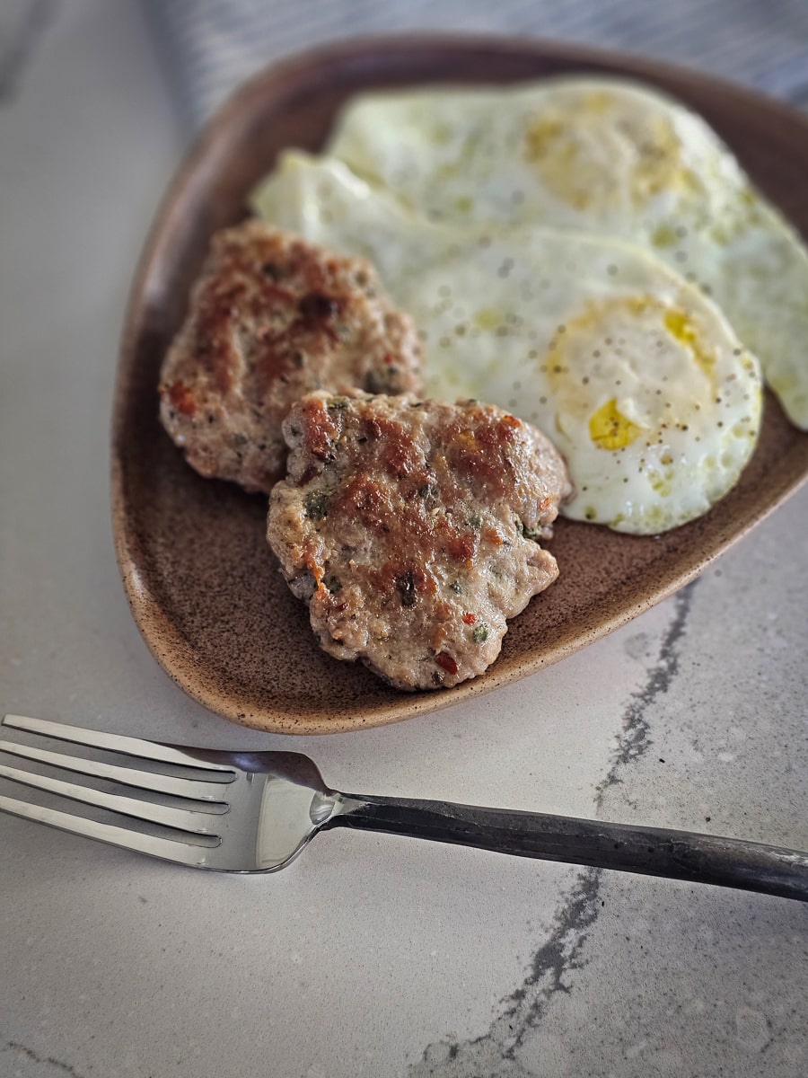 Homemade Sage Breakfast sausage on a plate with fried eggs.