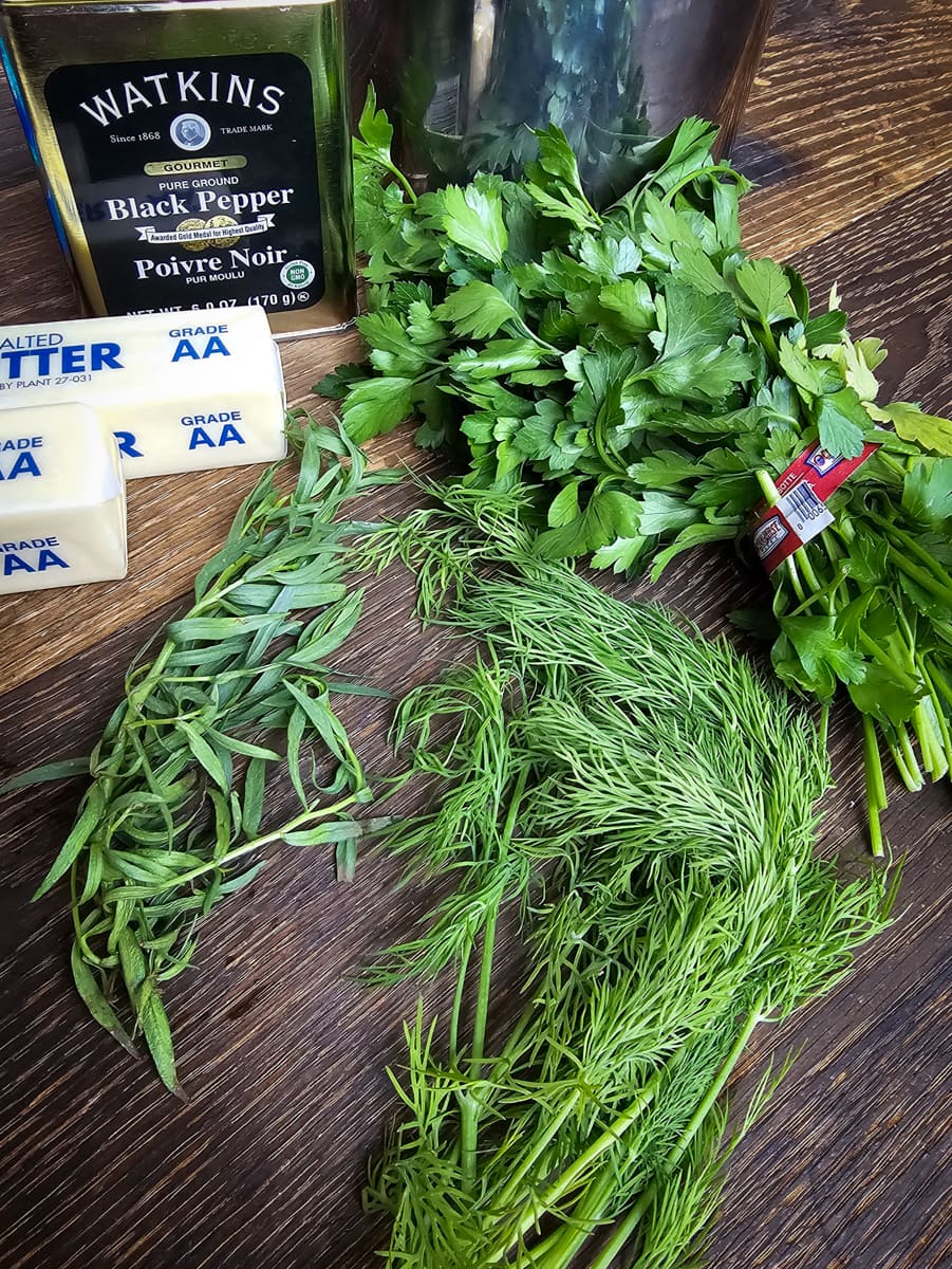 Fresh parsley, tarragon, and dill on a cutting board.