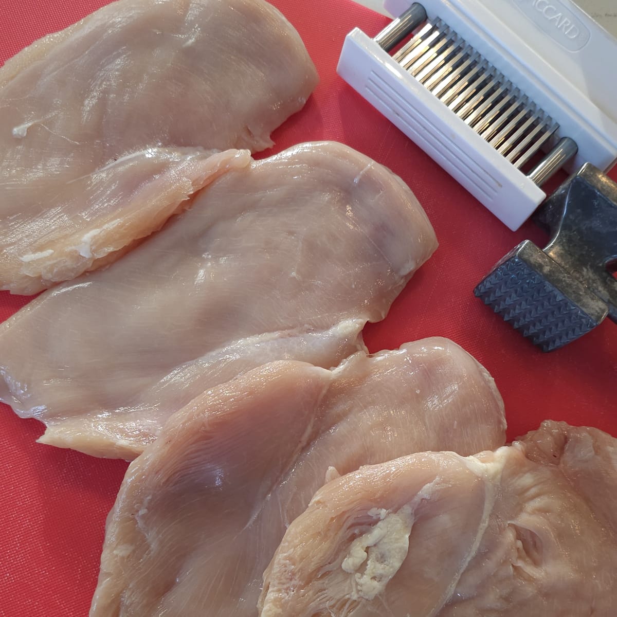 Chicken breasts pounded thin on a cutting board.